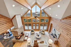 Living area featuring rustic walls, high vaulted ceiling, a fireplace, hardwood / wood-style floors, and recessed lighting