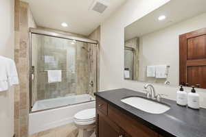Bathroom with vanity, bath / shower combo with glass door, and recessed lighting