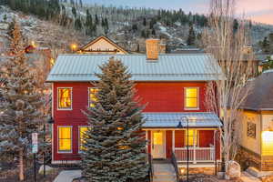 View of front of home with a standing seam roof, a chimney, and covered porch