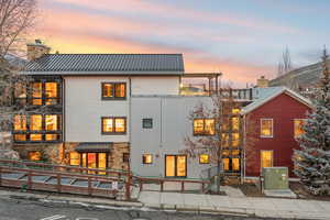 Rear view of house featuring a metal roof, a chimney, and stone siding