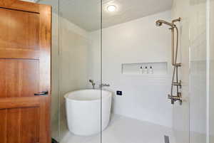 Full bathroom featuring a soaking tub, tiled shower, and tile walls