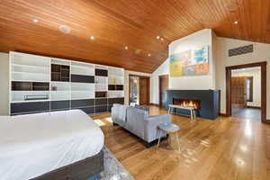 Bedroom with a lit fireplace, wood finished floors, recessed lighting, and a vaulted wood ceiling