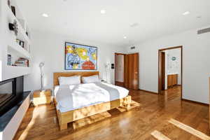 Bedroom featuring hardwood / wood-style floors, recessed lighting, and a fireplace with raised hearth