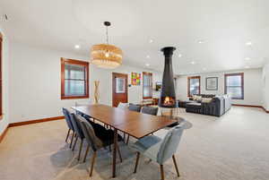 Dining area featuring light carpet, healthy amount of natural light, recessed lighting, and a wood stove