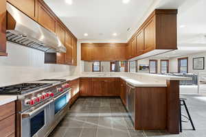 Kitchen featuring stainless steel appliances, a peninsula, a breakfast bar area, wood finish cabinets, and open floor plan