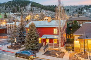 View of front facade featuring a standing seam roof, a metal roof, a porch, and a chimney