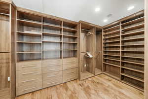 Walk in closet with light wood-style floors