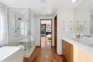 Ensuite bathroom with a freestanding bath, vanity, light wood finished floors, a stall shower, and recessed lighting