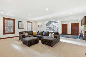 Living area with plenty of natural light, stairs, recessed lighting, and dark carpet