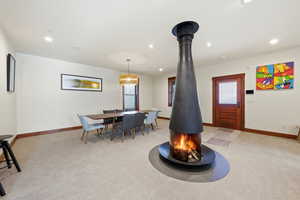 Dining area featuring healthy amount of natural light, recessed lighting, light carpet, and a wood stove