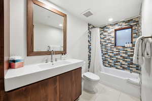 Bathroom featuring shower / bath combination with curtain, vanity, light tile patterned floors, and recessed lighting