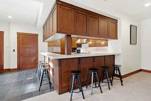 Kitchen with a kitchen bar, recessed lighting, light countertops, wood finish cabinets, and built in refrigerator