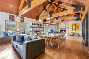 Living room featuring a lit fireplace, a wooden ceiling with exposed beams, hardwood / wood-style floors, and high vaulted ceiling