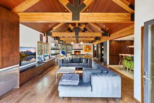 Living area featuring a high wooden beamed ceiling, wood finished floors, and a lit fireplace