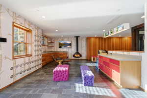 Interior space featuring wallpapered walls, a wood stove, and recessed lighting