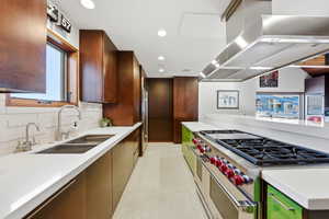 Kitchen featuring extractor fan, premium appliances, modern cabinets, recessed lighting, and light stone countertops