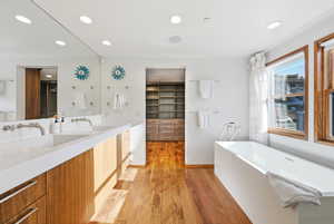 Full bath featuring a soaking tub, double vanity, recessed lighting, and light wood-type flooring