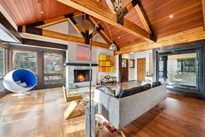 Living room featuring wood finished floors, a high wooden beamed ceiling, and a fireplace