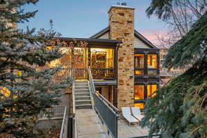Back of property at dusk with stairway, a balcony, and a chimney