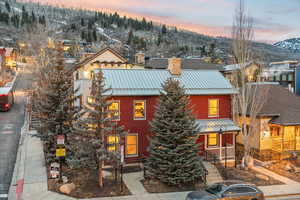 View of front facade featuring a standing seam roof, a metal roof, a chimney, and a porch