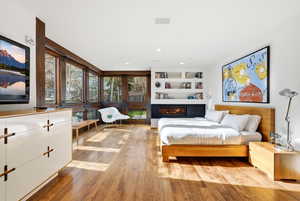 Bedroom featuring a glass covered fireplace, light wood finished floors, and recessed lighting