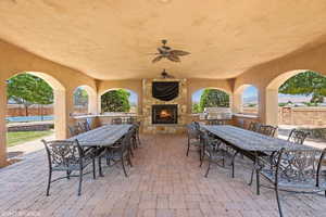 View of patio / terrace featuring area for grilling, outdoor dining area, an outdoor stone fireplace, and ceiling fan