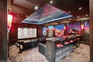 Cinema room with a raised ceiling, light carpet, and recessed lighting