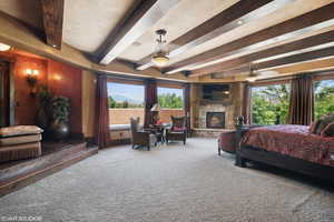 Bedroom featuring beam ceiling, carpet, and a fireplace