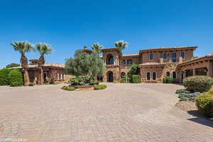 Mediterranean / spanish-style home with stucco siding, stone siding, curved driveway, and a tiled roof
