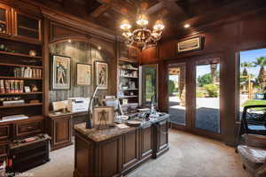Home office with built in shelves, light carpet, crown molding, coffered ceiling, and a chandelier