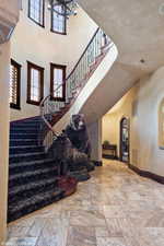 Stairs featuring stone tile flooring, arched walkways, and a towering ceiling