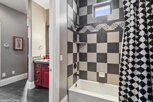 Full bath featuring vanity, shower / bath combo with shower curtain, and dark tile patterned floors