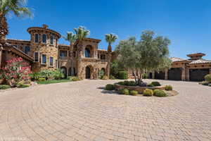 Mediterranean / spanish house featuring curved driveway, stone siding, stucco siding, a balcony, and a tiled roof