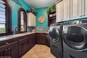 Laundry area with cabinet space, washer and dryer, and light tile patterned floors
