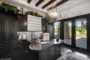 Office area with dark wood-style floors, beamed ceiling, and a chandelier