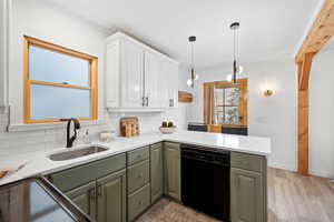 Kitchen featuring green cabinets, white cabinets, black dishwasher, decorative backsplash, and light wood finished floors