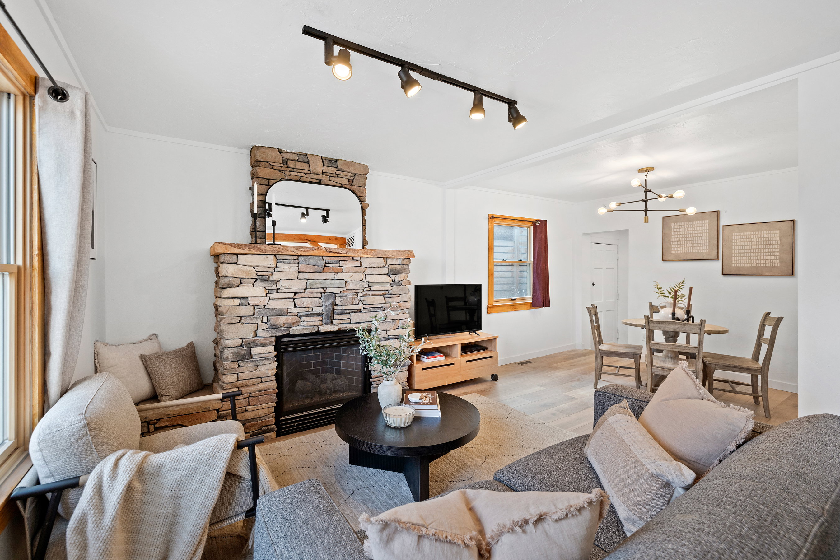 Living room featuring a fireplace, rail lighting, wood finished floors, and a chandelier