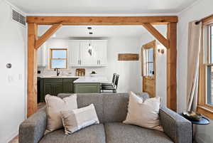 Kitchen with green cabinets, open floor plan, white cabinets, tasteful backsplash, and decorative light fixtures