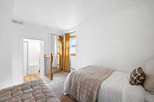 Carpeted bedroom with a baseboard heating unit