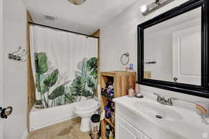 Bathroom with vanity, shower / tub combo with curtain, a textured ceiling, and light tile patterned floors