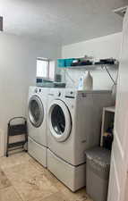 Washroom featuring a textured ceiling and washing machine and clothes dryer