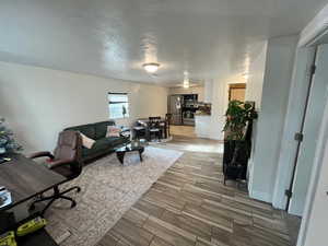 Living area featuring wood finish floors, a textured ceiling, and a desk