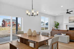 Dining space with light wood-type flooring, a ceiling fan, a fireplace, and suspended lighting