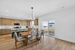 Dining area with hanging lights and light wood finished floors