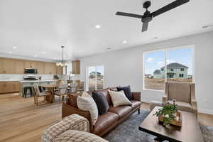 Living room with light wood-style floors, a chandelier, and ceiling fan