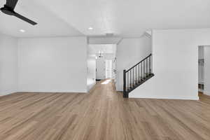 Unfurnished living room featuring light wood-style flooring, stairway, recessed lighting, and a ceiling fan