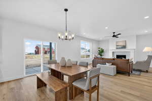 Dining space with light wood-style floors, a fireplace, ceiling fan, and hanging lights
