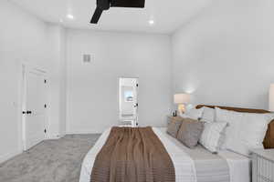Bedroom with carpet, a high ceiling, ensuite bath, ceiling fan, and recessed lighting