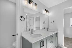 Bathroom featuring double vanity, a stall shower, and light colored carpet