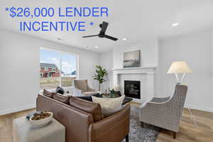 Living area featuring light wood-style floors, ceiling fan, a glass covered fireplace, and recessed lighting